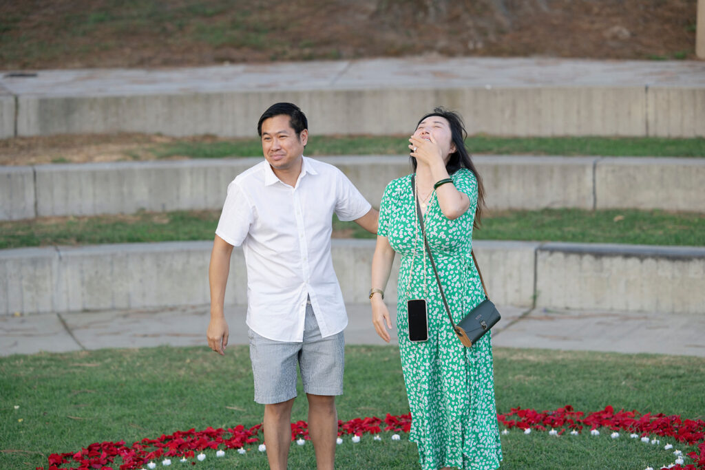 Woman acts surprised as man leads her to surprise proposal at Dana Point.