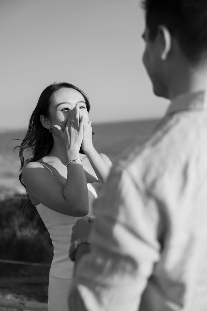 Woman reacts to surprise proposal on Crystal Cove beach captured by Orange County proposal photographer.