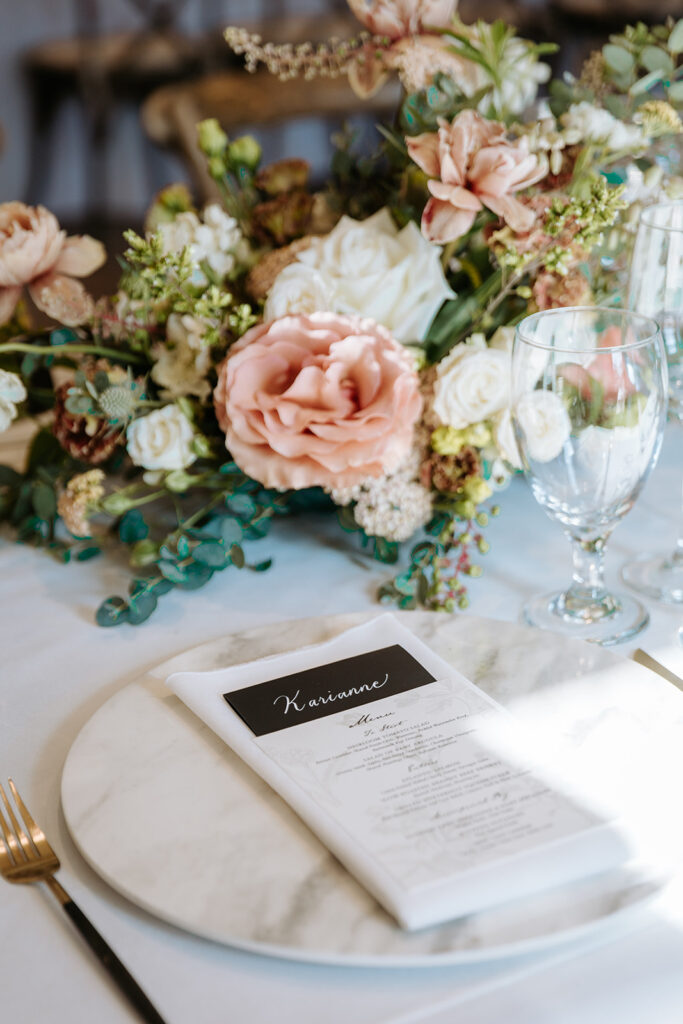 close up of tablescape of simple white linens and tableware and lush floral arrangements for wedding reception