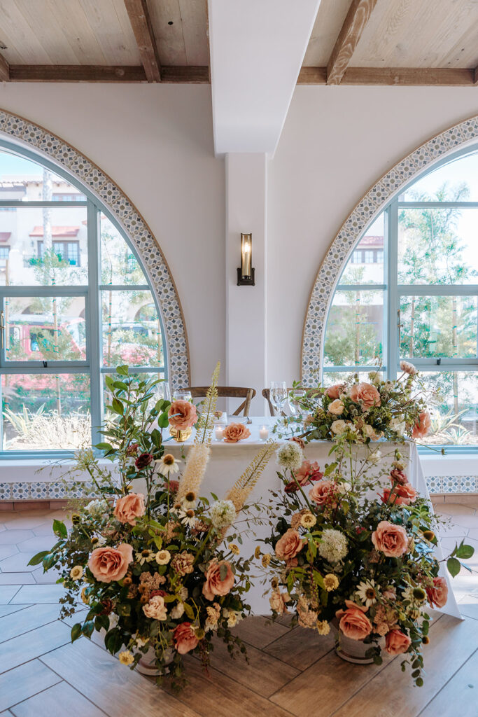 close up of sweetheart tablescape set up with simple white linens and tableware and lush floral arrangements on and around the table for wedding reception