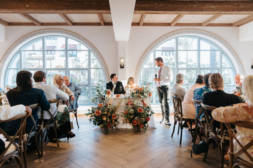 bride and groom sitting at sweetheart table during speeches