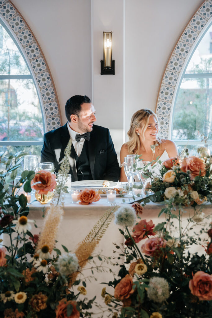 bride and groom sitting at sweetheart table during speeches