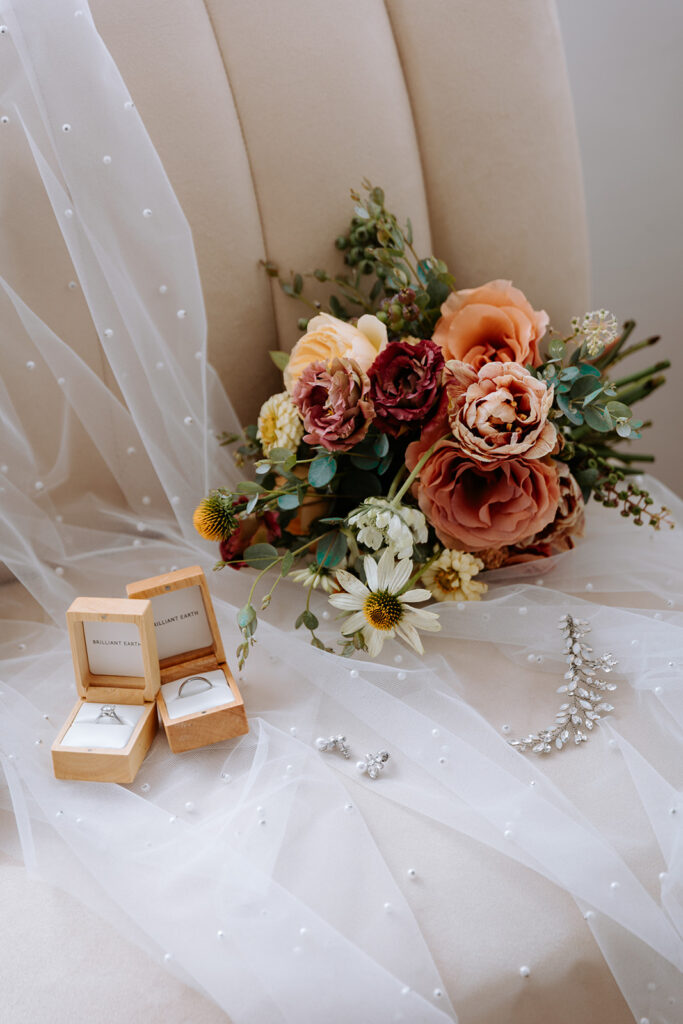 bridal bouquet with blush, dusty pink and peach florals, wedding rings and bridal accessories