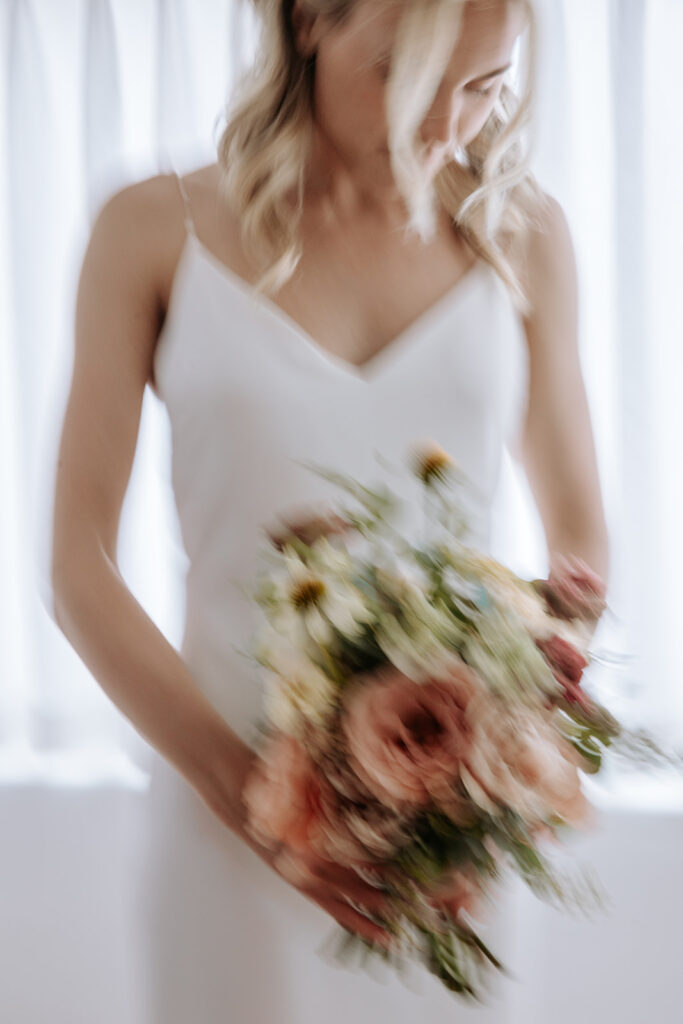 blurry close up of bride in dress holding bouquet