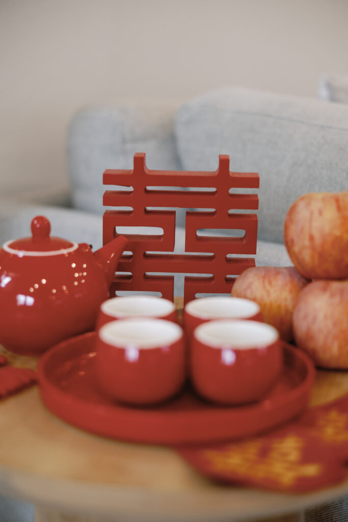 A vibrant tea ceremony setup with red cups, apples, and a double happiness symbol