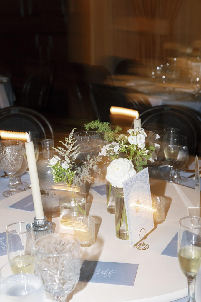 a wedding tablescape with florals, taper candles and greenery and table number and place card stationery