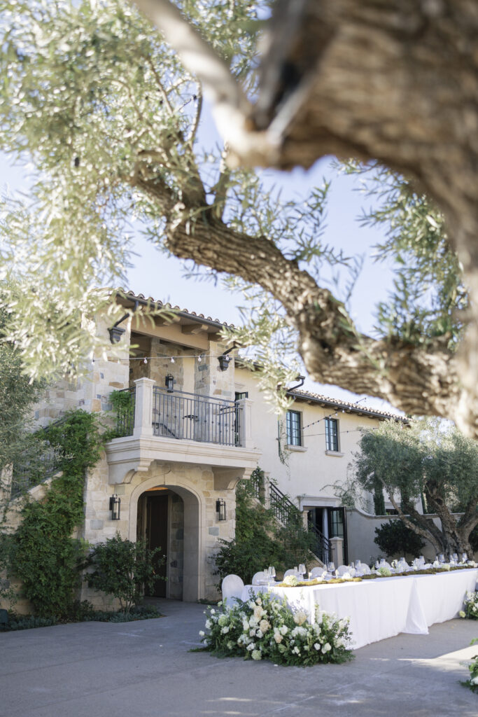 A Mediterranean-style villa surrounded by greenery, featuring a greenery and white floral-lined table