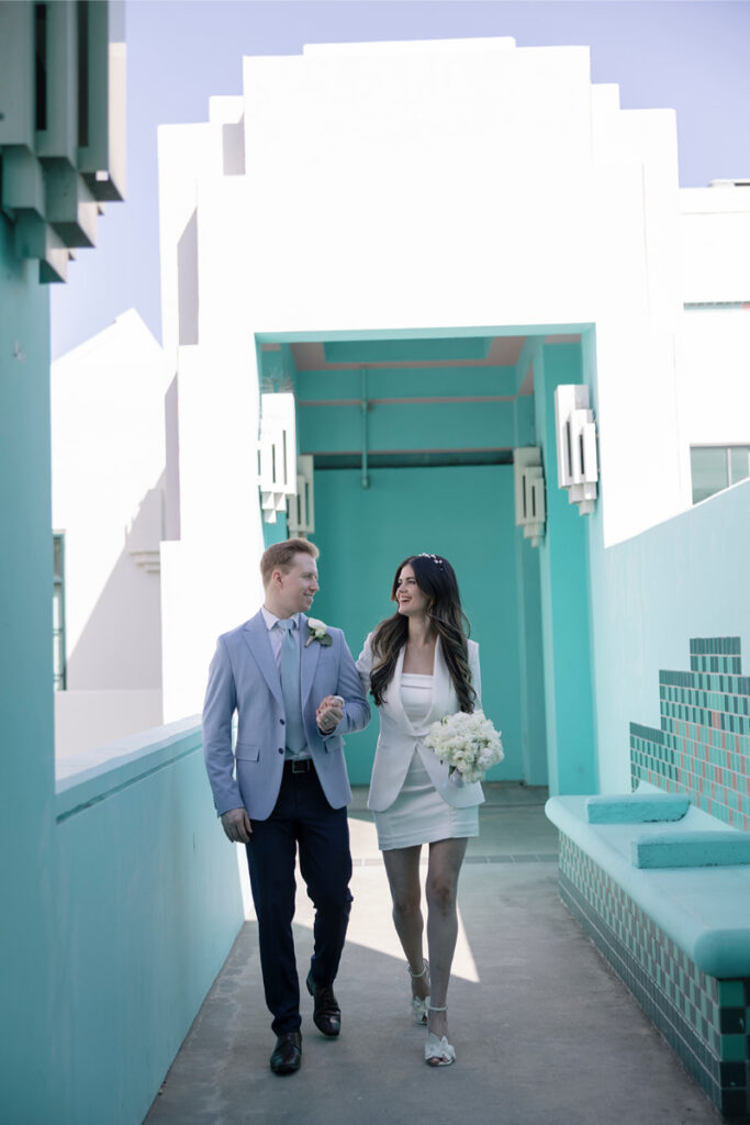 Hand in hand, the couple strolls through a turquoise walkway, celebrating their city hall elopement in Orange County.