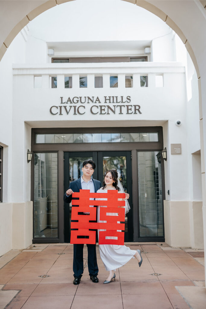 Bride and groom pose together in front of Laguna Hills Civic center sign. 