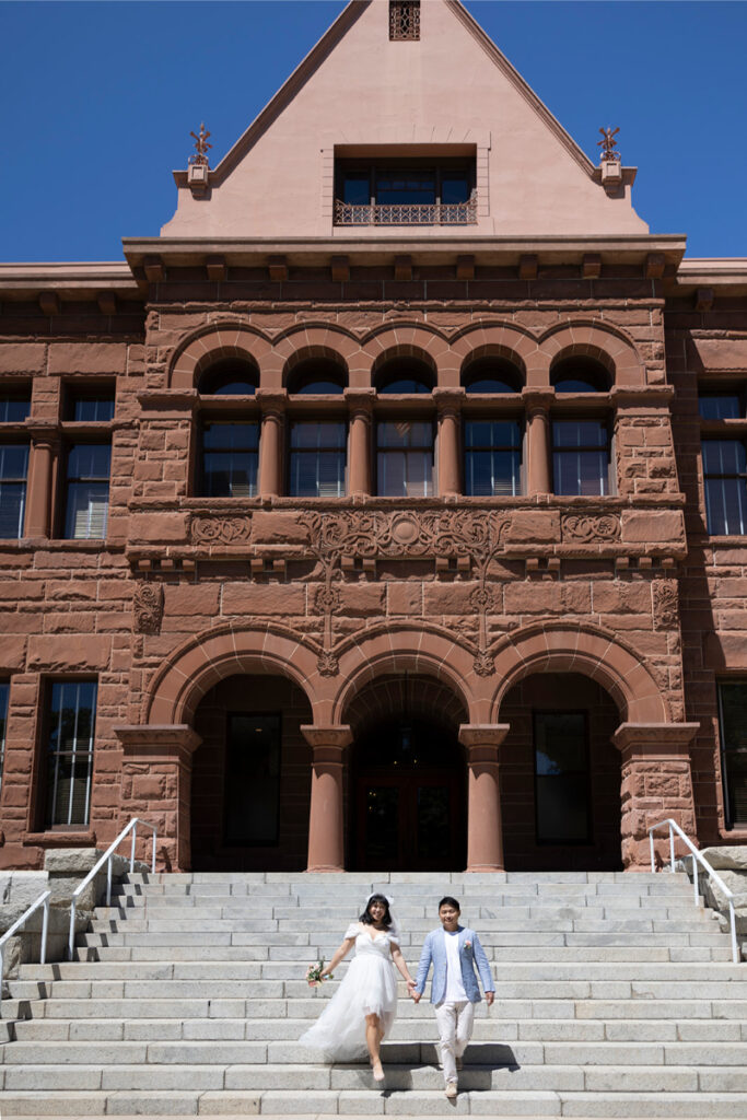 Bride and groom walking down steps outside of Old Orange County Courthouse after their elopement. 