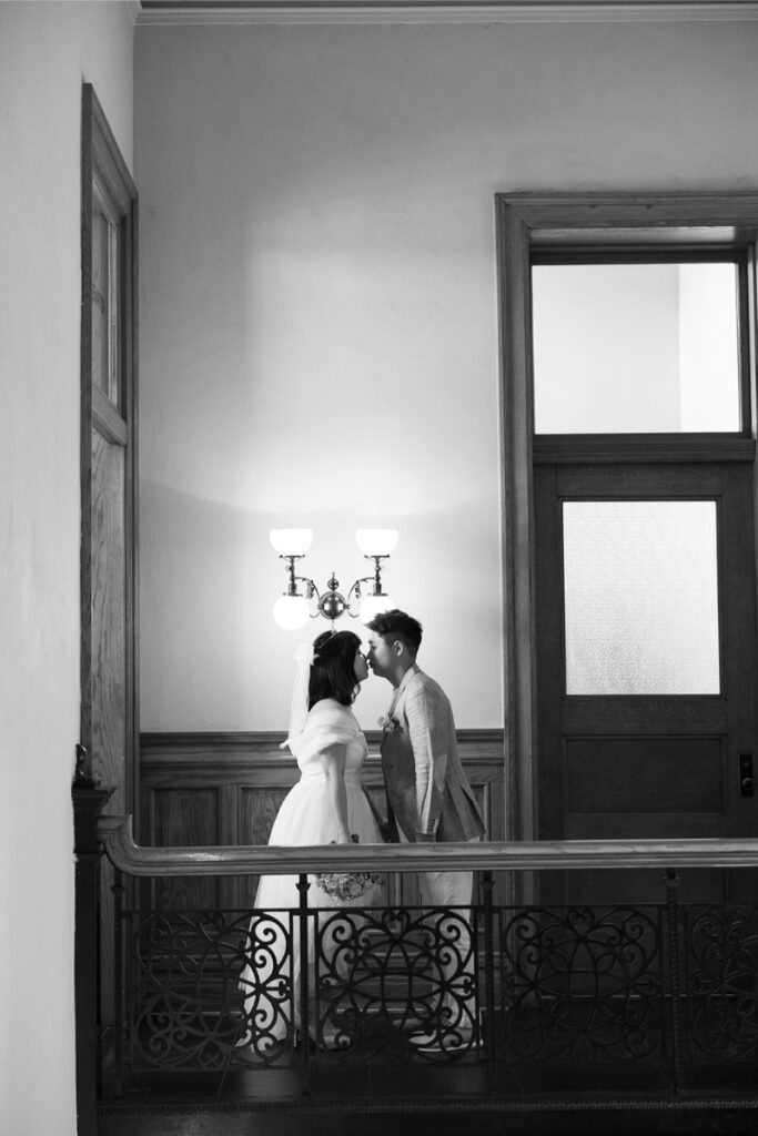 Black and white photo of bride and groom sharing kiss in Old Orange County Courthouse before their elopement. 