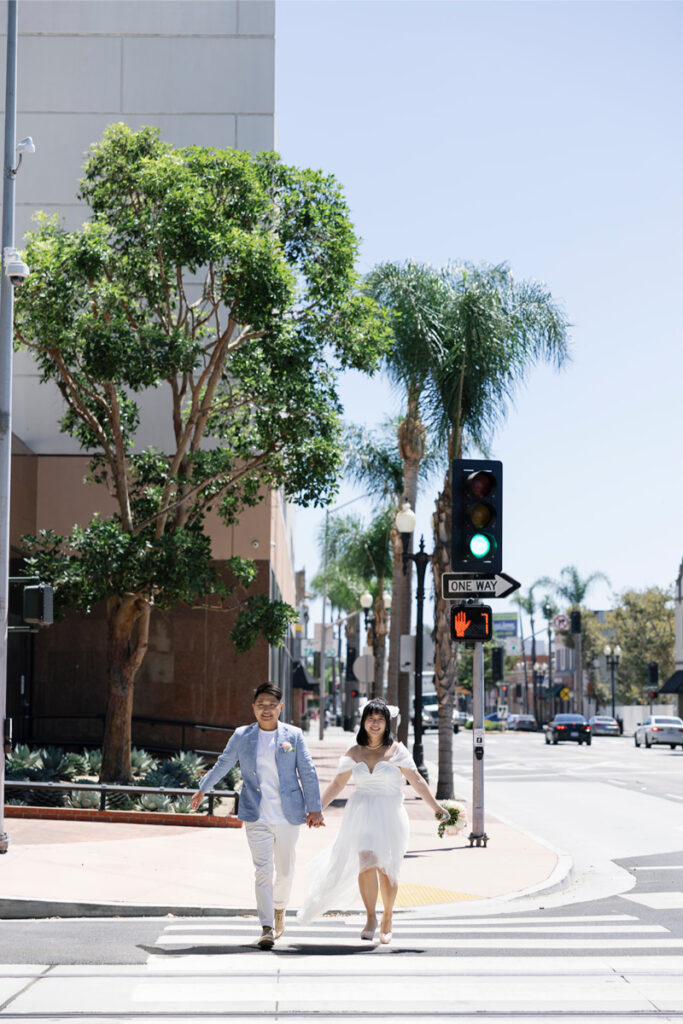 Bride and groom walk along cross walk after their city hall elopement. 