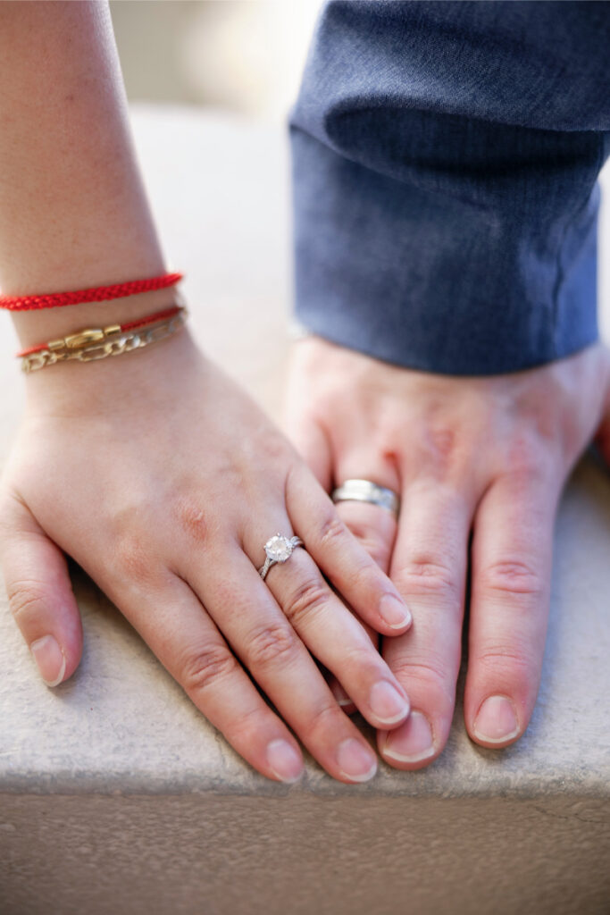 A close-up of the couple’s hands shows their wedding rings. 