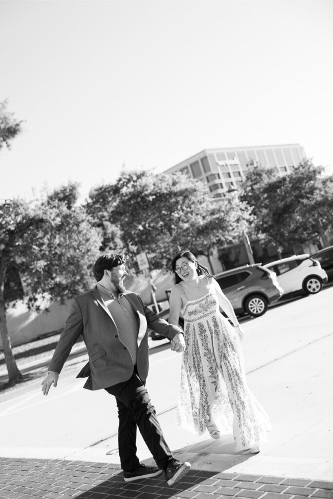 Candidly laughing, the couple walks together on a city street near Pasadena City Hall, capturing their elopement joy.