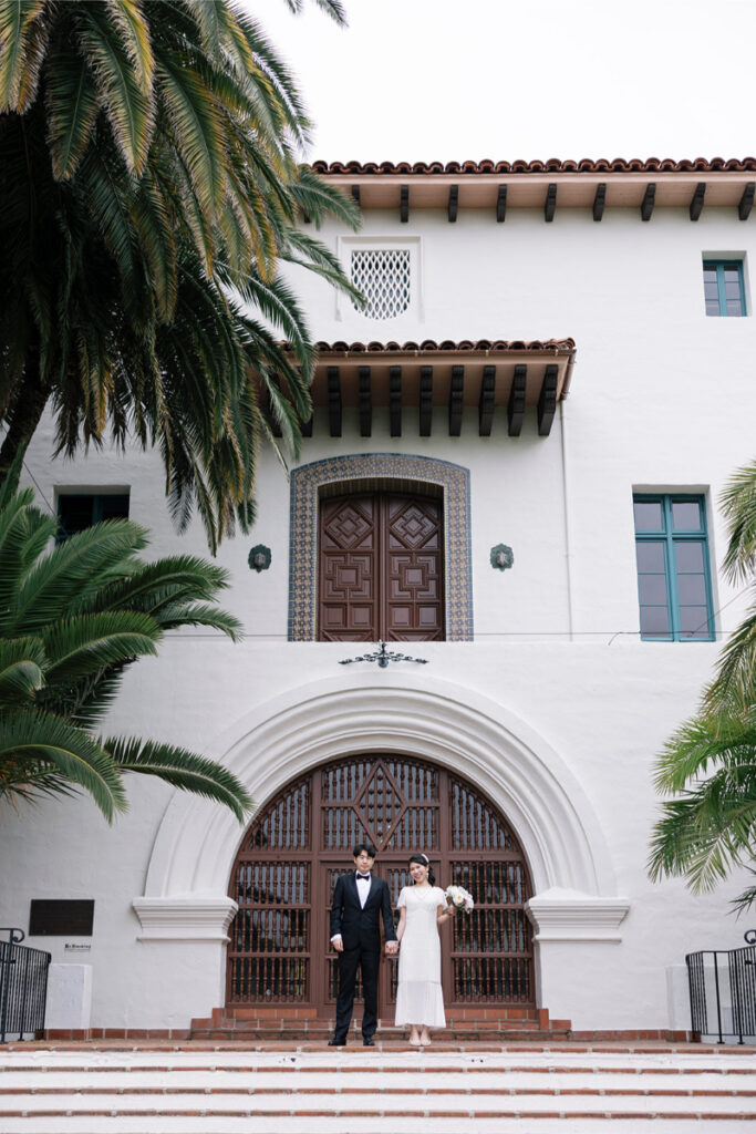 Bride and groom posing in front of Santa Barbara Courthouse. 