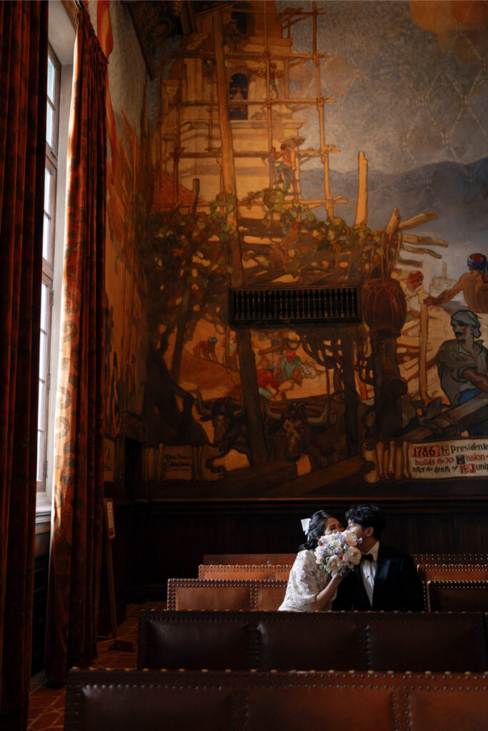 Bride and groom share a kiss behind the bride's bouquet after their elopement at Santa Barbara Courthouse. 