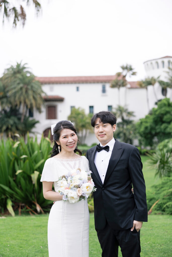 Bride and groom pose together outside Santa Barbara Courthouse after their elopement. 