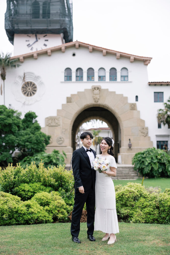 Bride and groom posing in front of Santa Barbara Courthouse. 